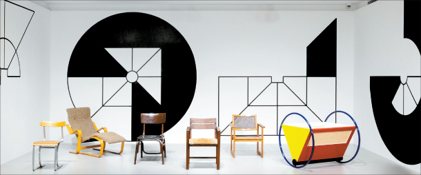 A photo of several chairs in front of a white wall painted with black geometric images