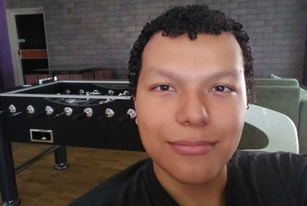 A selfie of Freddy wearing a black T-shirt. Behind him, a foosball table can be seen.