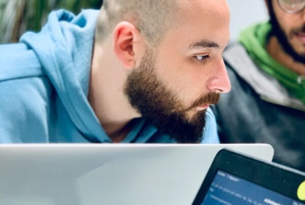 man in blue hoodie looking at macbook